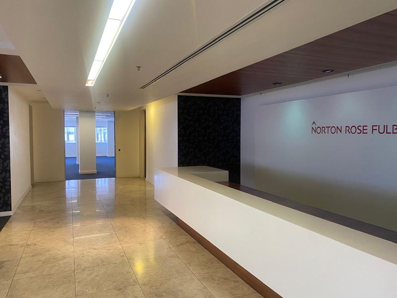 Professional office reception area featuring a built-in reception desk, polished stone flooring, and modern recessed lighting with wood-accented ceiling details.
