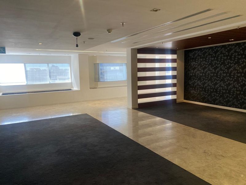 Spacious open-plan office area featuring a mix of tiled and carpeted flooring, recessed lighting, and a modern decorative feature wall with a slatted divider.