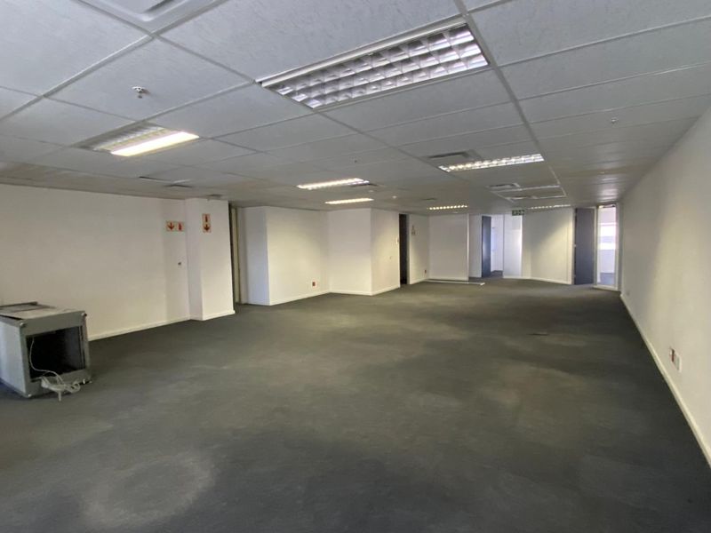 A large, vacant open-plan office space featuring suspended ceilings, recessed lighting, and carpeted flooring, ready for custom fit-out.