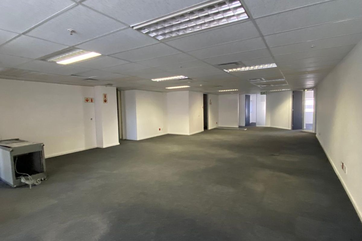 A large, vacant open-plan office space featuring suspended ceilings, recessed lighting, and carpeted flooring, ready for custom fit-out.