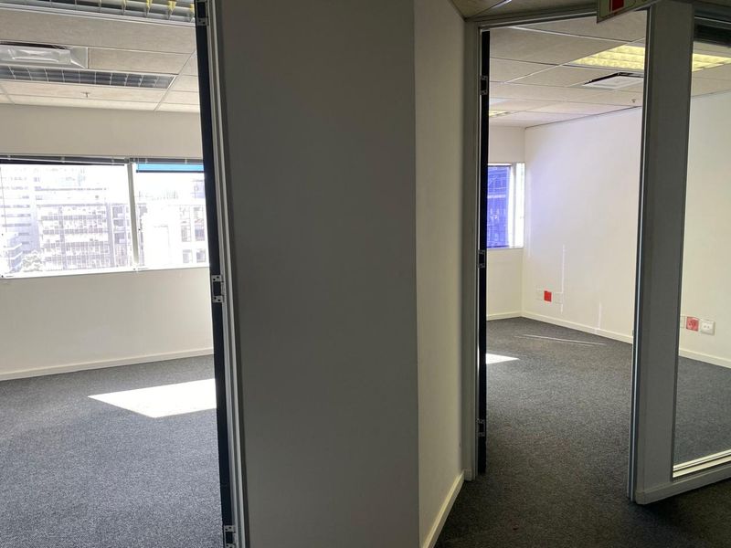 A vacant office space featuring carpeted flooring, suspended ceilings, and glass partition walls, offering a clean and professional environment for business operations.