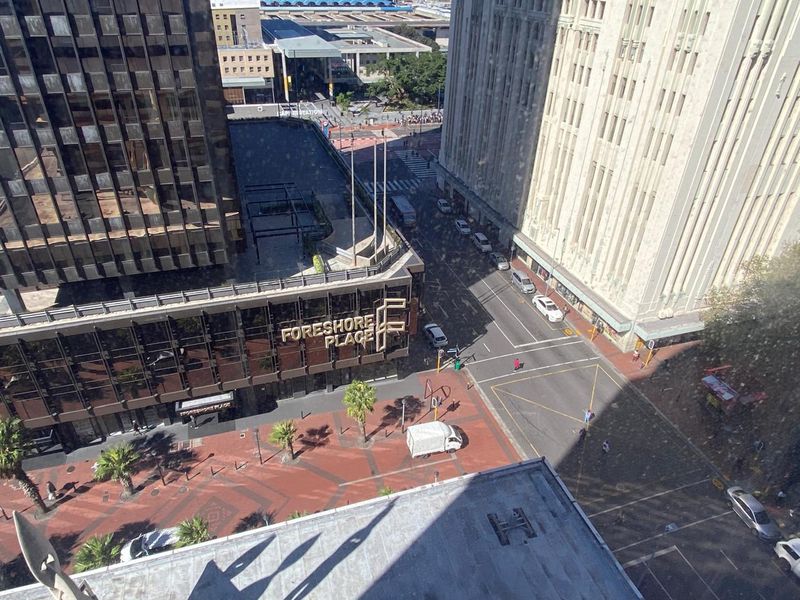 An elevated aerial view overlooking a city street intersection, surrounding commercial office buildings, and a paved pedestrian plaza area.