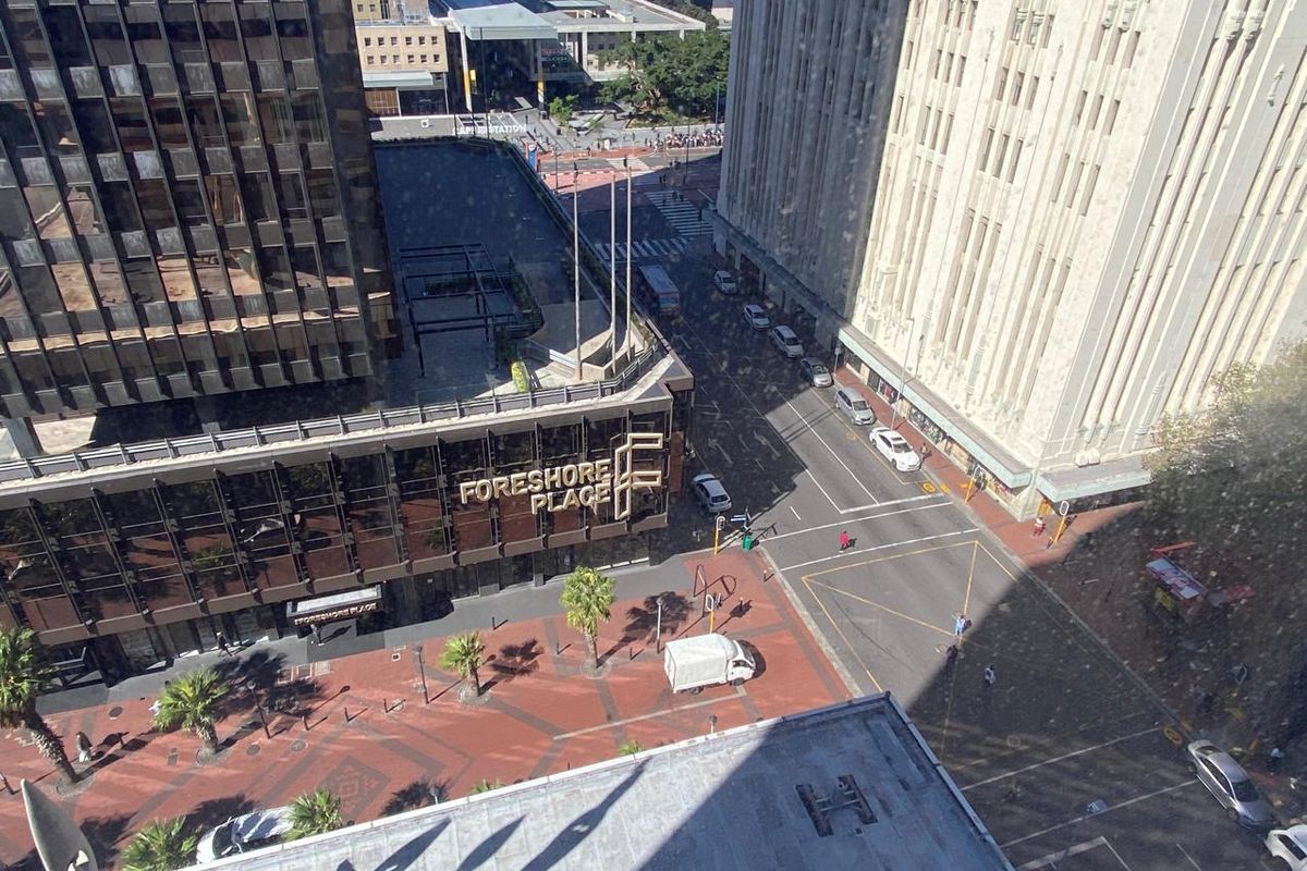 An elevated aerial view overlooking a city street intersection, surrounding commercial office buildings, and a paved pedestrian plaza area.