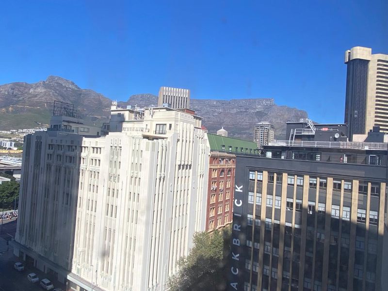An elevated urban view showcasing surrounding office buildings and the iconic Table Mountain range in the background.