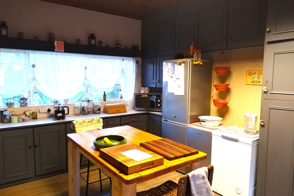 A functional kitchen featuring dark grey cabinetry, ample counter space, and a central wooden island, providing a practical layout for meal preparation.