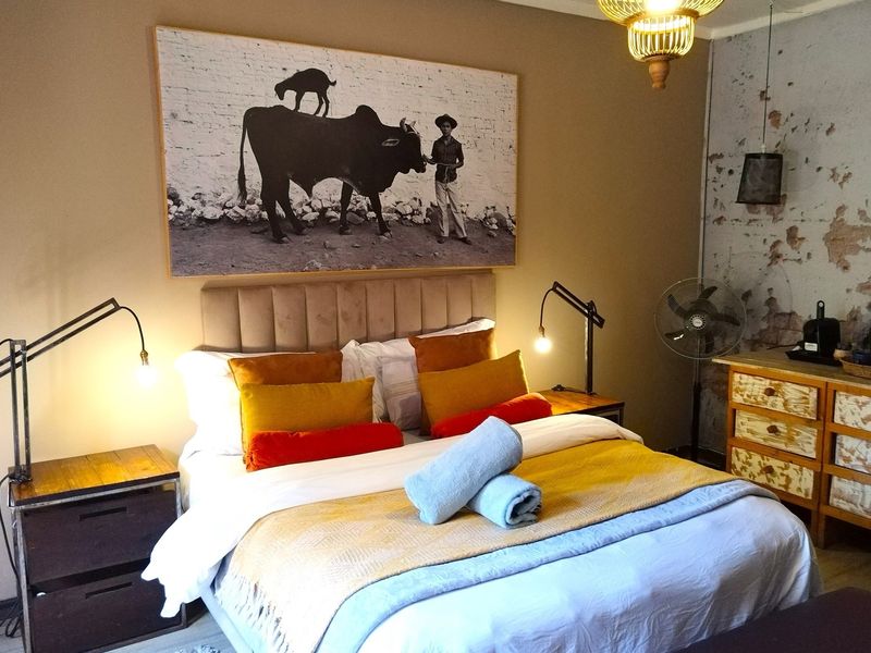A cozy bedroom featuring a double bed, bedside lighting, and a unique textured wall finish, creating a rustic and inviting atmosphere.