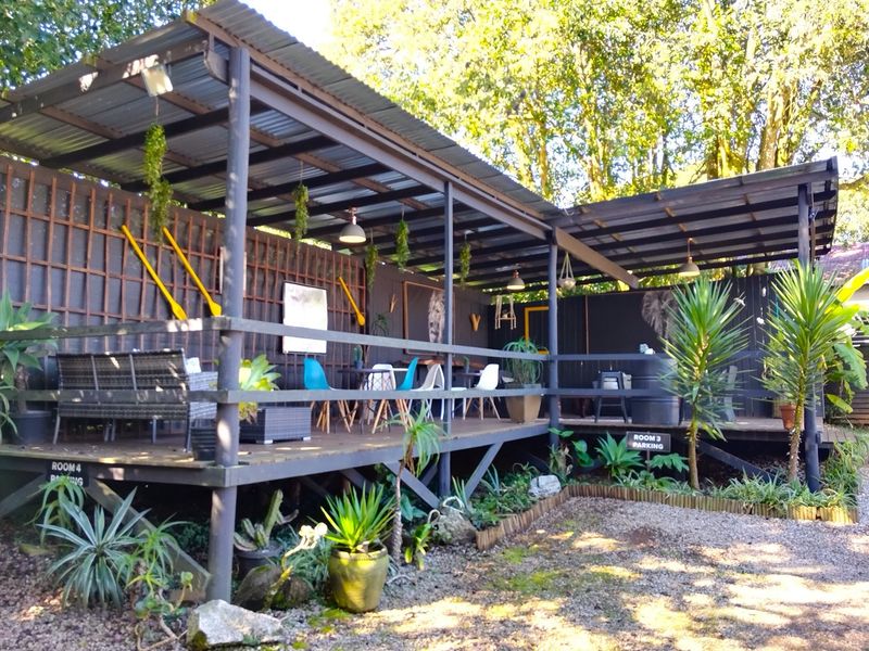 A covered outdoor patio area featuring a timber deck structure, providing a shaded space for relaxation and guest access to parking areas.