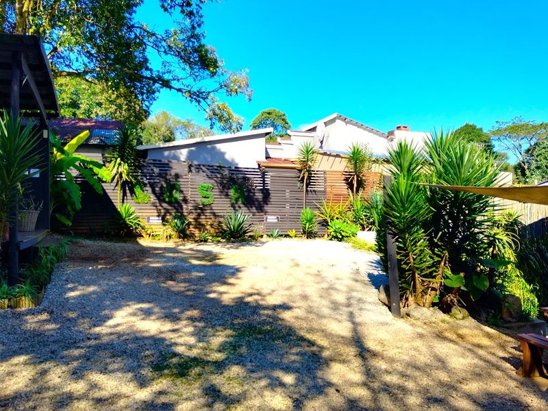 A gravel courtyard area featuring timber slat fencing, established garden landscaping, and a covered outdoor structure.