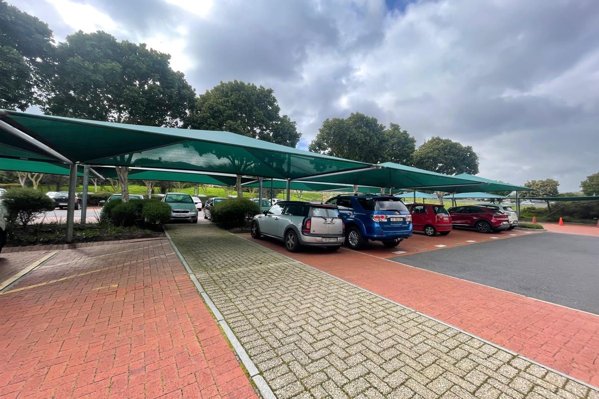 Outdoor parking area featuring multiple shade cloth carports and paved surfaces, providing sheltered vehicle storage for the office property.