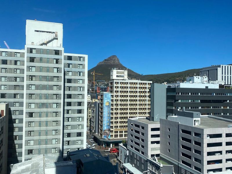 An elevated urban view showcasing surrounding office buildings and city infrastructure with a prominent mountain backdrop.