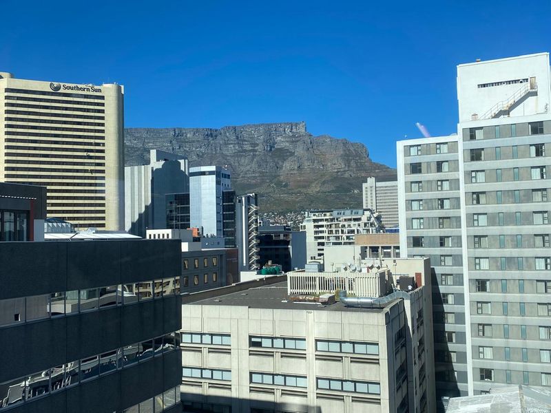 An elevated urban view showcasing surrounding office buildings and a prominent mountain backdrop.