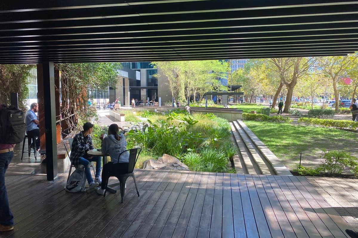 A covered outdoor timber deck area overlooking a landscaped garden and office park grounds, providing a pleasant transition between indoor and outdoor spaces.