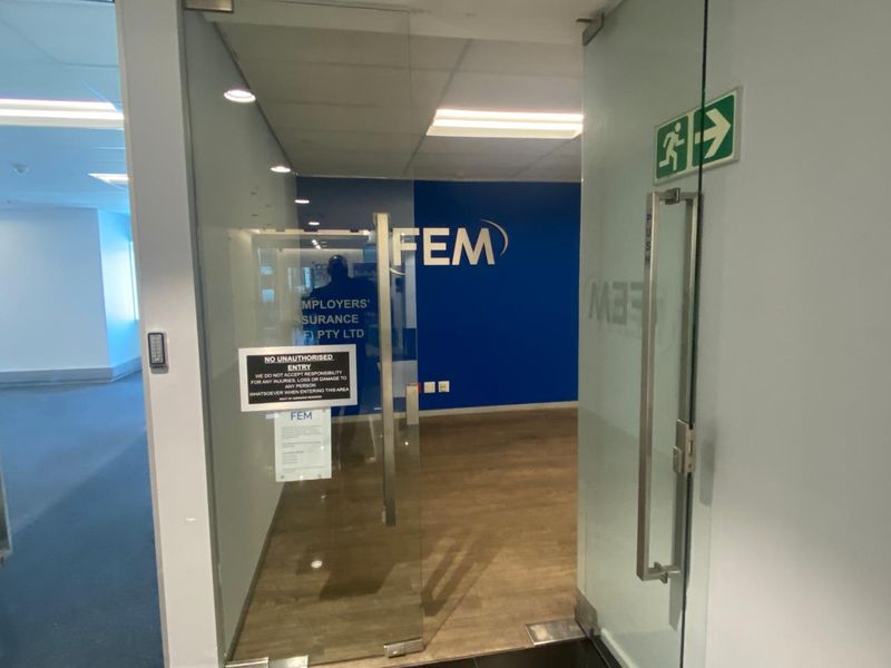Professional office entrance featuring a glass door, access control system, and modern laminate flooring with a clean, corporate aesthetic.