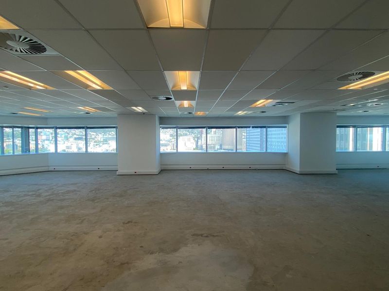 Spacious open-plan office area featuring a suspended ceiling, recessed lighting, and expansive windows offering city views, ready for custom fit-out.