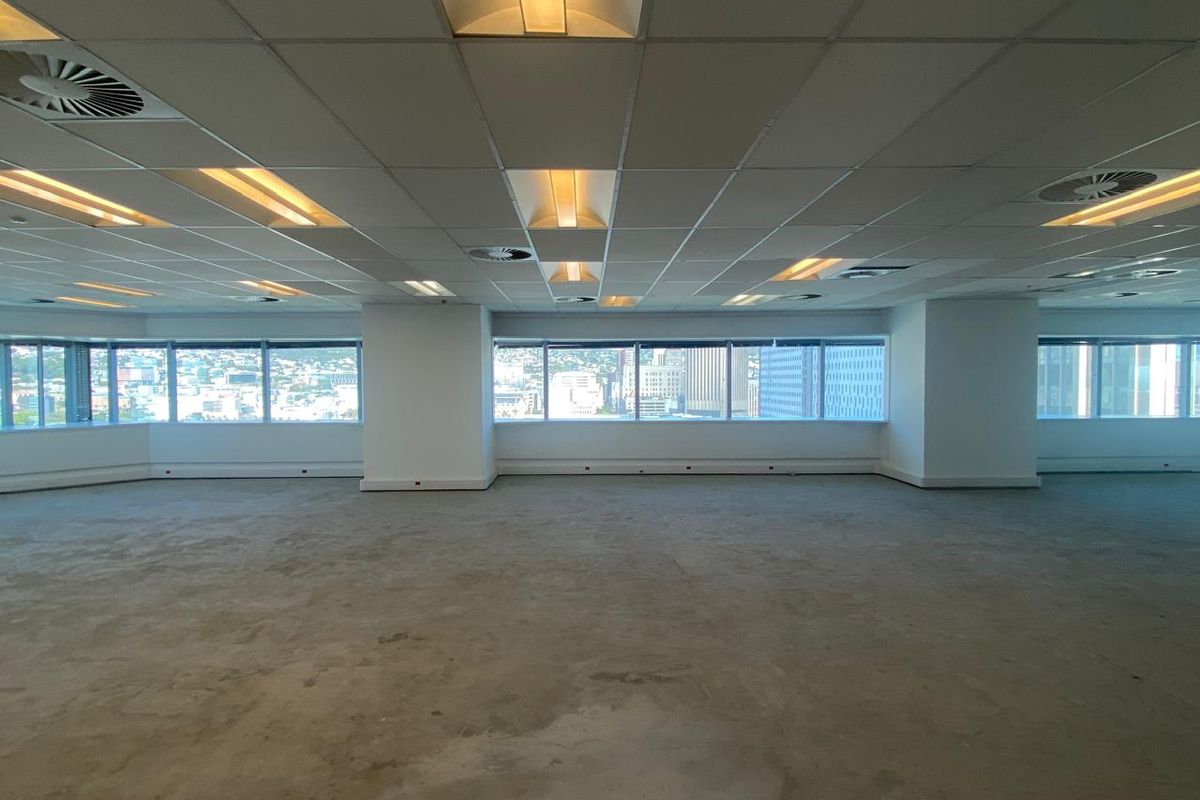 Spacious open-plan office area featuring a suspended ceiling, recessed lighting, and expansive windows offering city views, ready for custom fit-out.