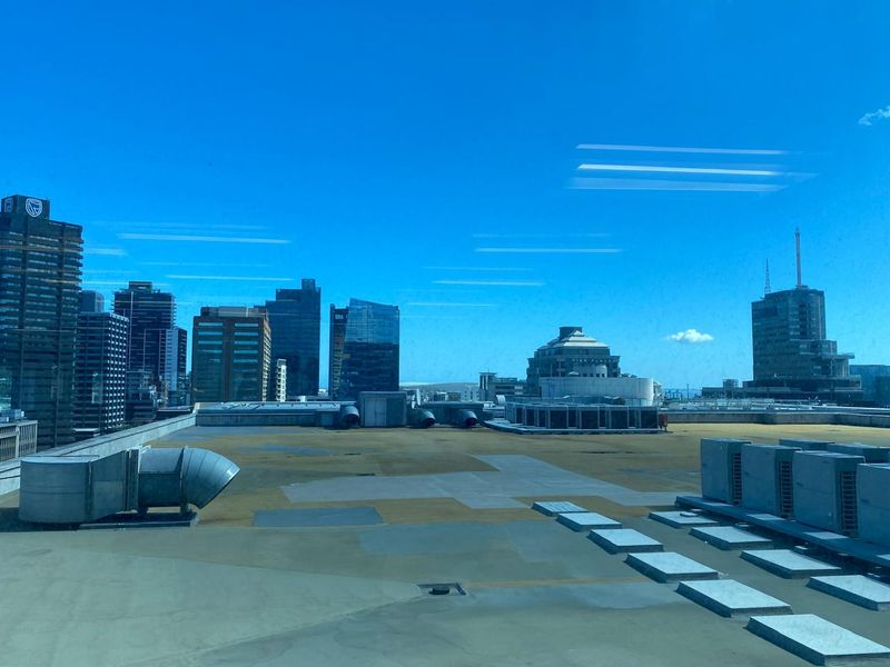 An elevated view overlooking a flat commercial roof with HVAC infrastructure and a surrounding city skyline.