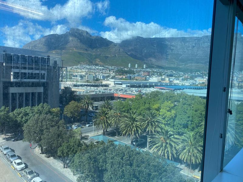 A clear elevated view of the city and mountain range captured through a large office window.
