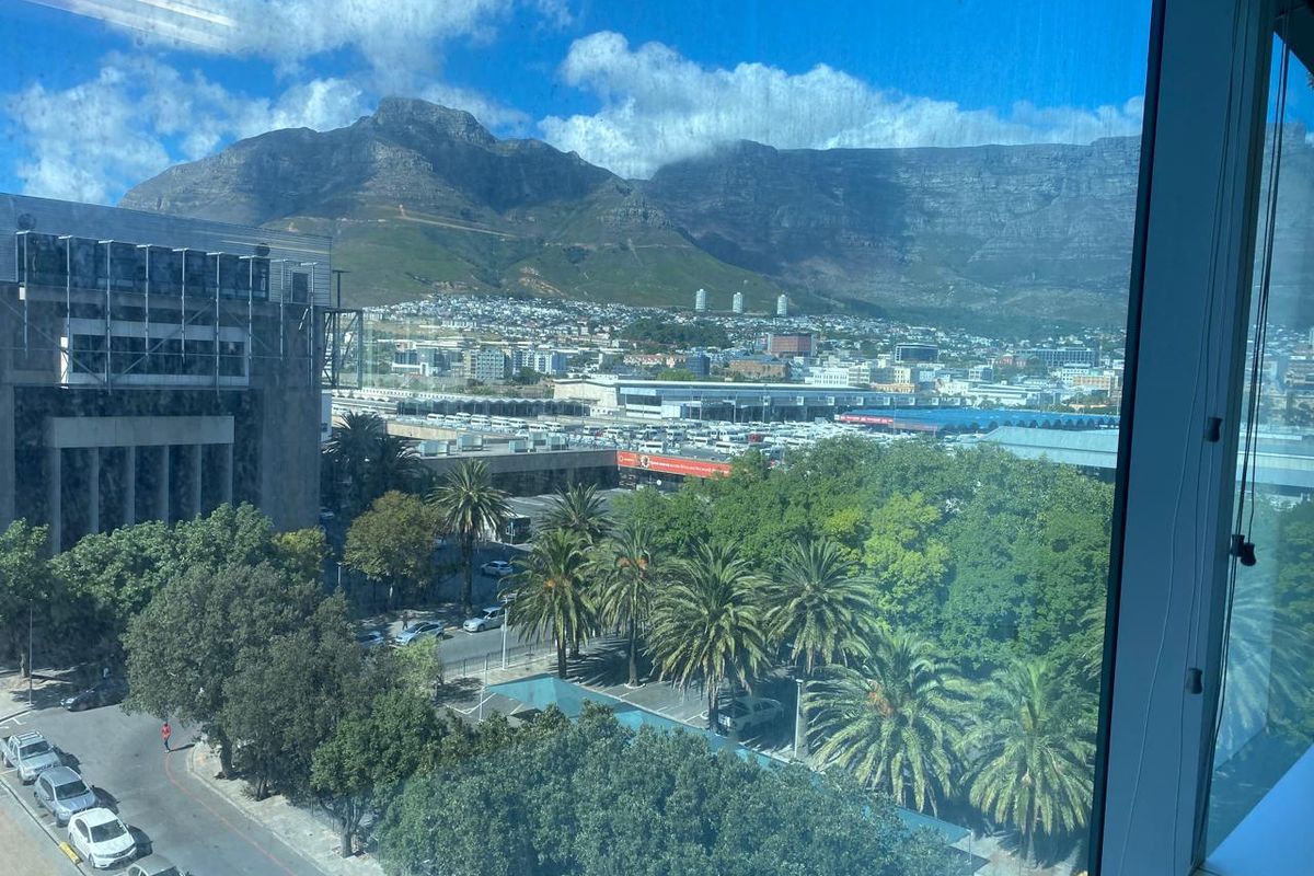 A clear elevated view of the city and mountain range captured through a large office window.