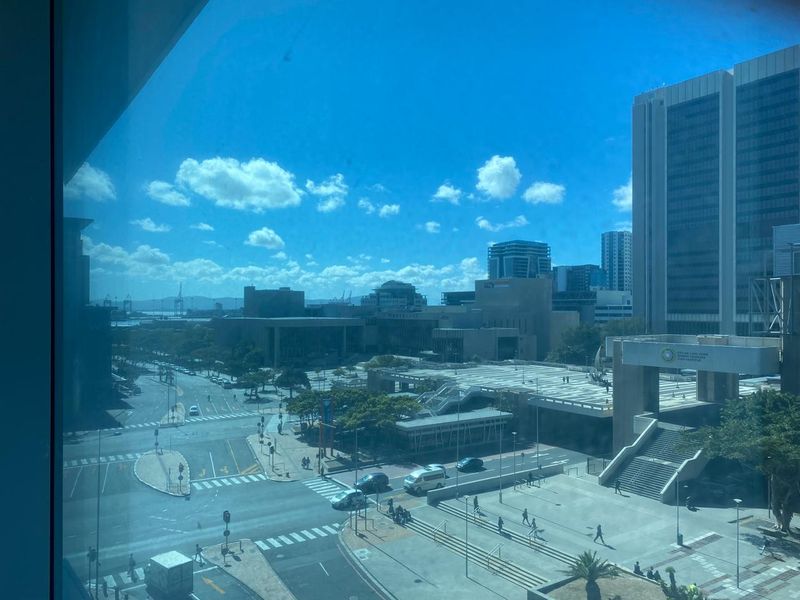 An elevated city view looking out over urban streets, public plazas, and surrounding high-rise office buildings.