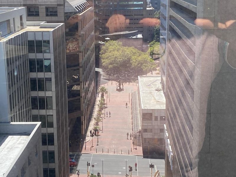 An elevated urban view looking down onto a pedestrian plaza and surrounding office buildings in a city center.