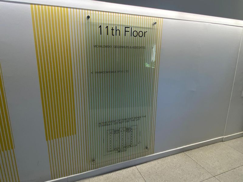 A clean office hallway featuring a wall-mounted acrylic directory sign for the 11th floor and modern tiled flooring.