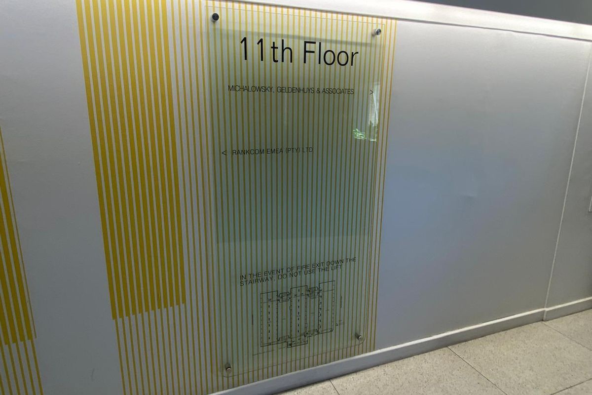 A clean office hallway featuring a wall-mounted acrylic directory sign for the 11th floor and modern tiled flooring.