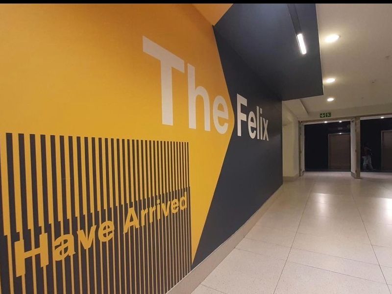 A modern commercial hallway featuring tiled flooring, recessed ceiling lighting, and prominent branded wall signage.