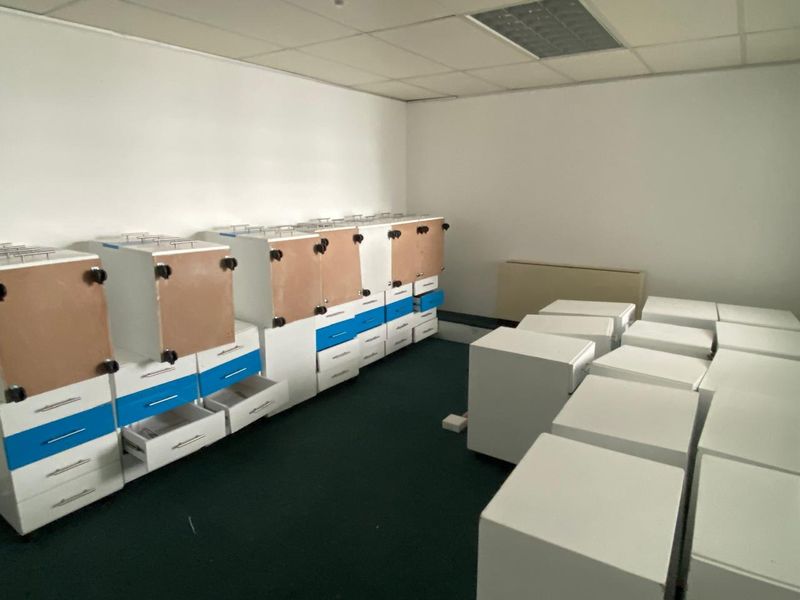 A utility or storage room featuring a suspended ceiling, recessed lighting, and multiple rows of built-in white cabinetry with blue accents.