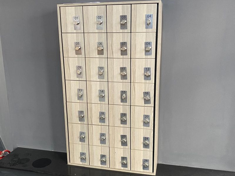 A wall-mounted unit featuring twenty-eight individual numbered storage lockers with integrated keyed locks, suitable for commercial or office use.