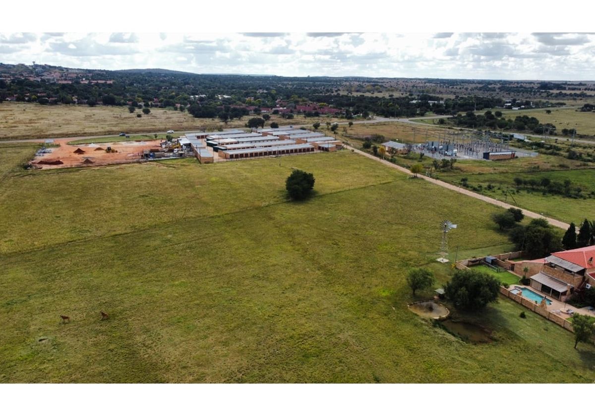 Aerial view of a large commercial property featuring storage units, an electrical substation, and a residential area with a swimming pool and windmill.