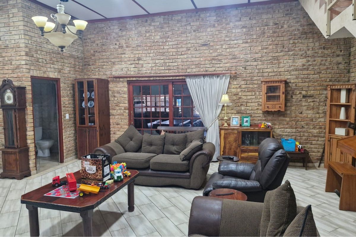 Spacious living room featuring exposed brick walls, tiled flooring, and large sliding glass doors that provide natural light and access to the exterior.