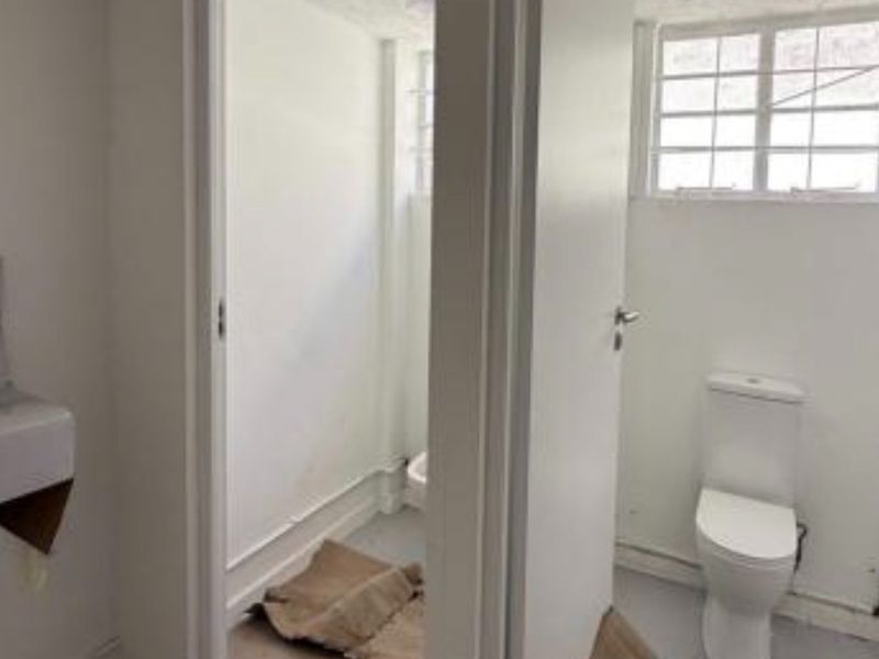 A functional bathroom space featuring a toilet and basin, currently in a basic, unfinished condition requiring cosmetic updates and flooring completion.