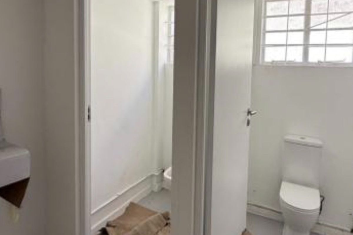 A functional bathroom space featuring a toilet and basin, currently in a basic, unfinished condition requiring cosmetic updates and flooring completion.
