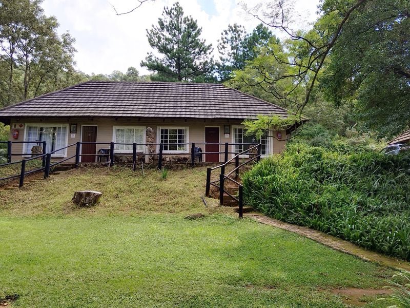 A lodge-style building featuring a tiled roof, covered veranda, and direct access to a lush, landscaped garden setting.