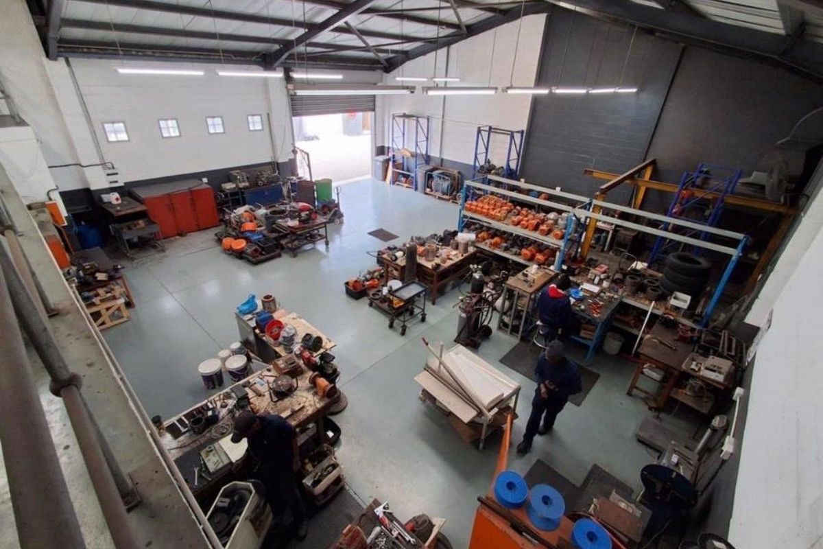 Spacious industrial workshop featuring high ceilings with exposed steel trusses, durable epoxy flooring, and large roller shutter access for operational efficiency.