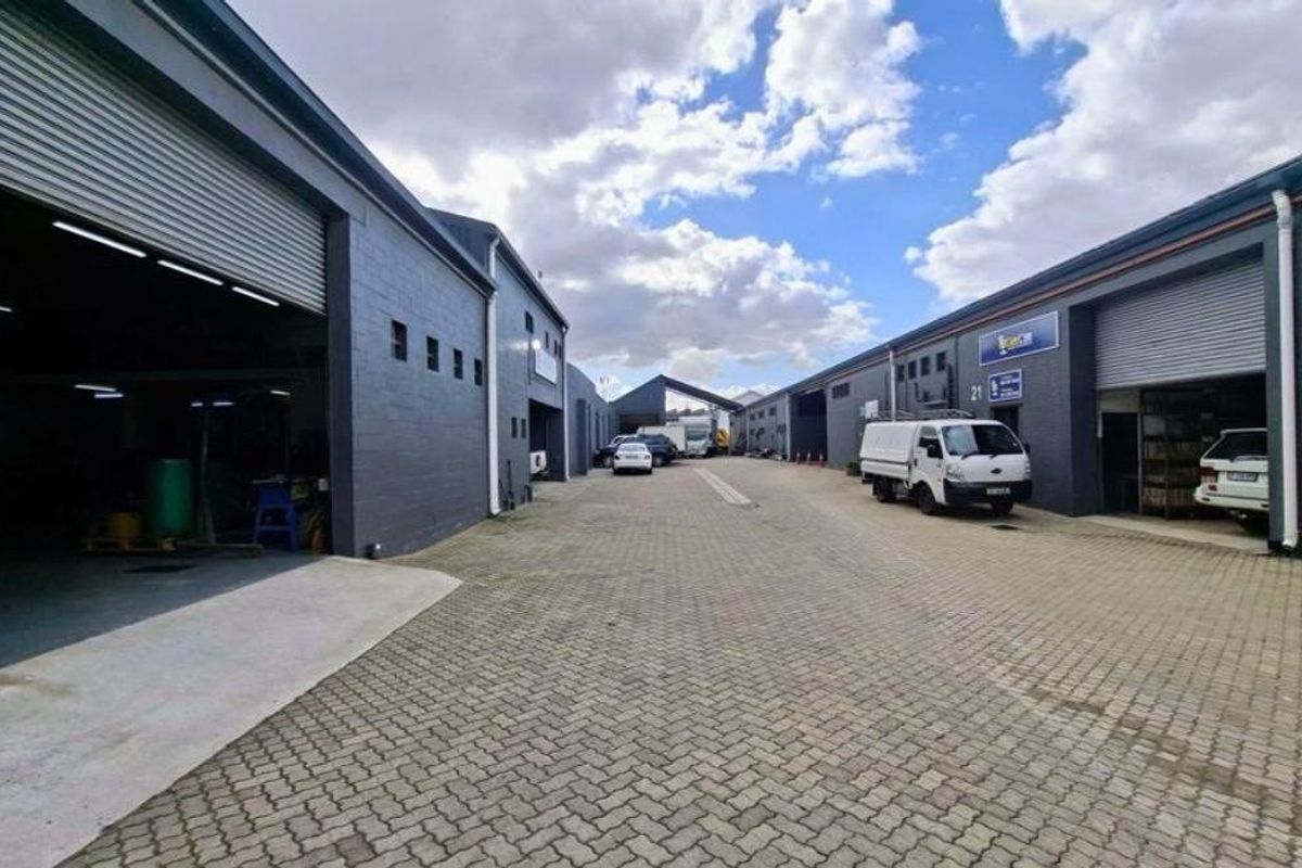 An industrial complex featuring multiple units with roller shutter doors and a paved common driveway area.