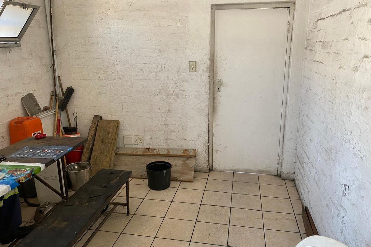 A functional utility space featuring tiled flooring and painted brick walls, suitable for storage or workshop use.