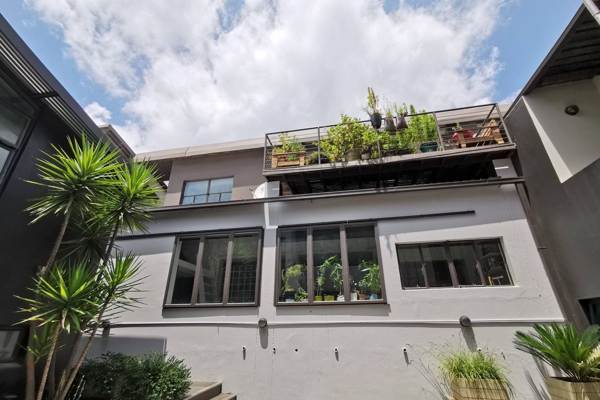 A view of the rear exterior facade featuring a metal balcony, dark-framed windows, and a painted exterior finish.