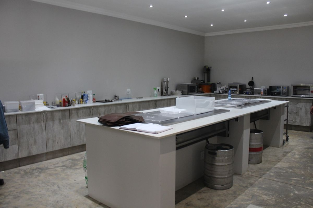 Commercial kitchen area featuring extensive cabinetry, stone-topped preparation islands, and recessed ceiling lighting, suitable for professional food preparation or catering operations.