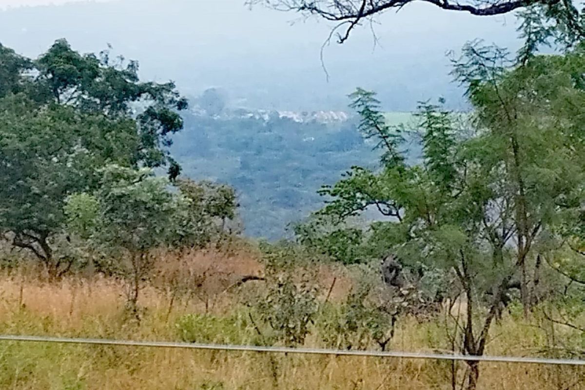 A scenic landscape view overlooking a valley with natural vegetation and distant residential development.