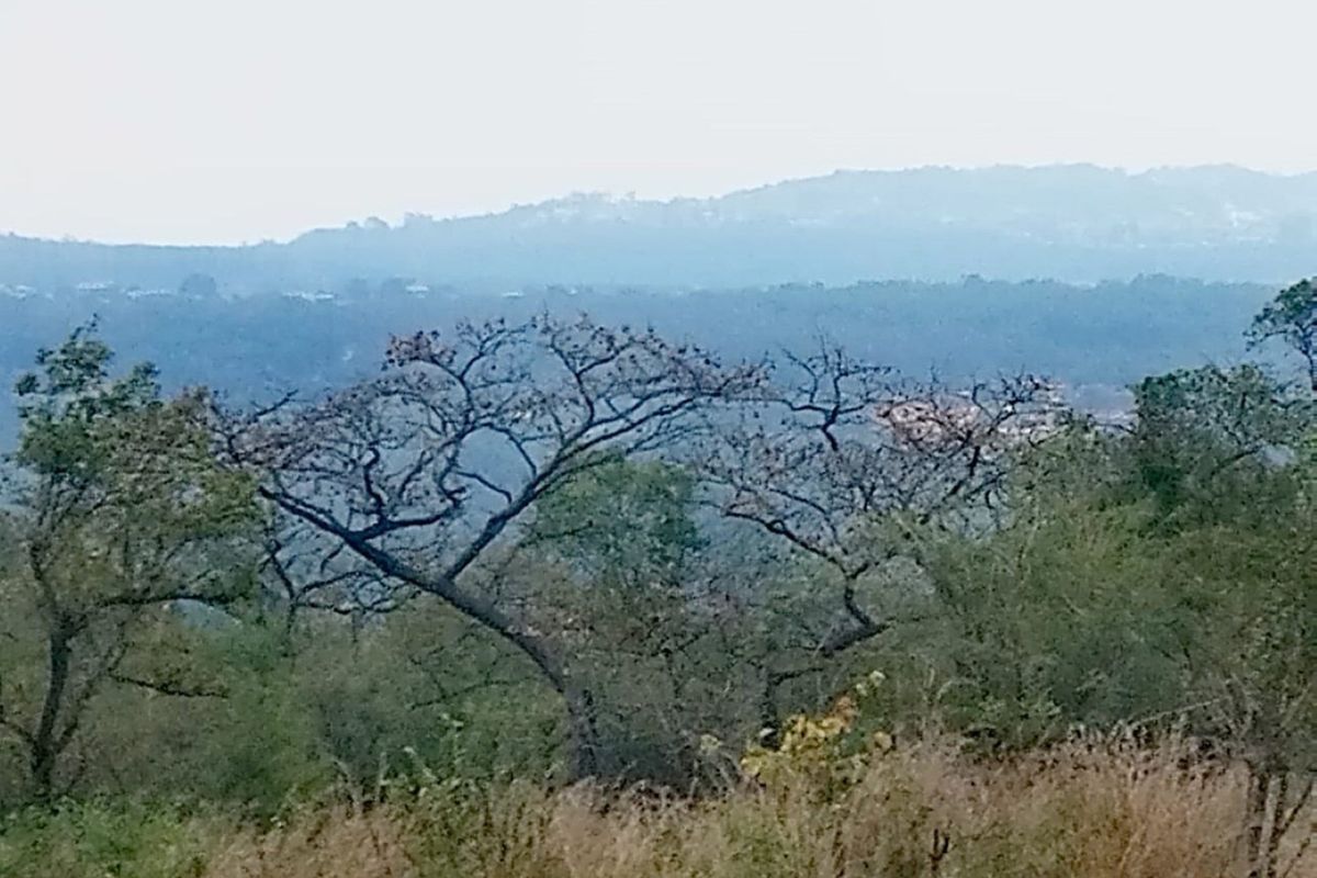 A scenic landscape view overlooking rolling hills and natural vegetation, showcasing the property's elevated position and surrounding environment.