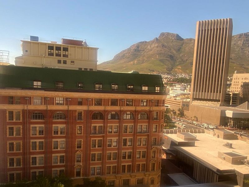 An elevated city view showcasing surrounding office buildings and a prominent mountain backdrop.