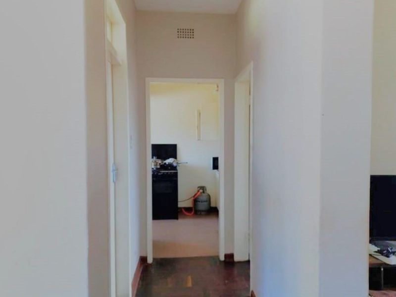 A narrow interior hallway with timber flooring, providing access to adjacent rooms within the property.