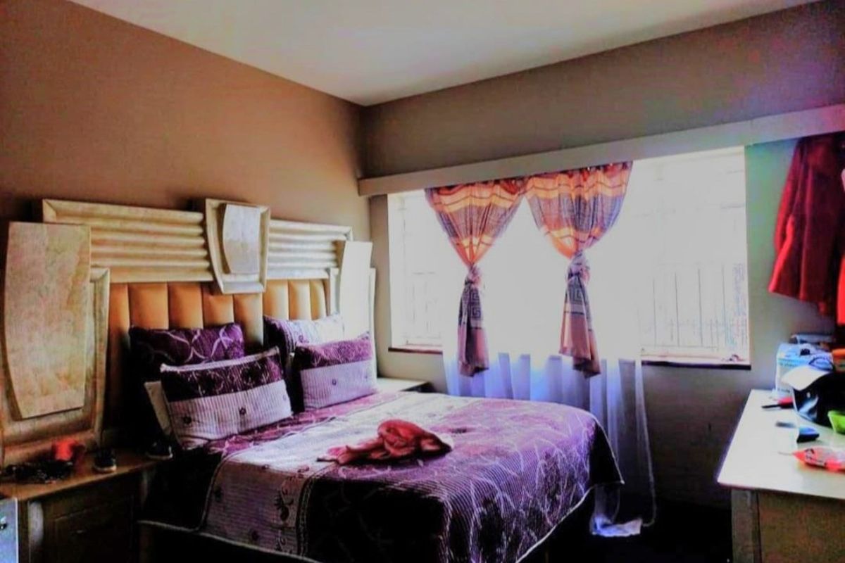 A bedroom featuring a large built-in headboard and a window with natural light.