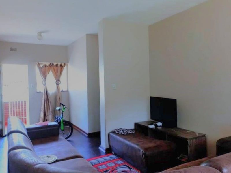 A living room area featuring laminate flooring and neutral wall finishes, providing a functional space for relaxation.
