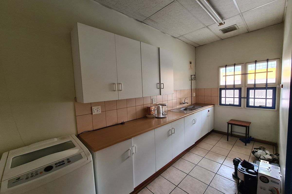 Functional kitchen area featuring laminate countertops, built-in cabinetry, stainless steel sink, and ceramic tiling throughout.