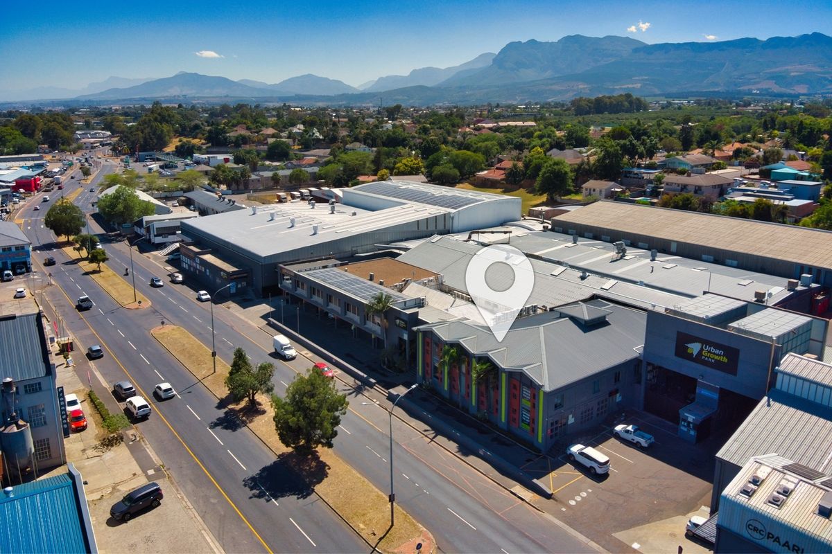 Aerial view of a commercial retail park featuring multiple warehouse-style buildings, metal roofing, solar panel installations, and convenient street-front access.
