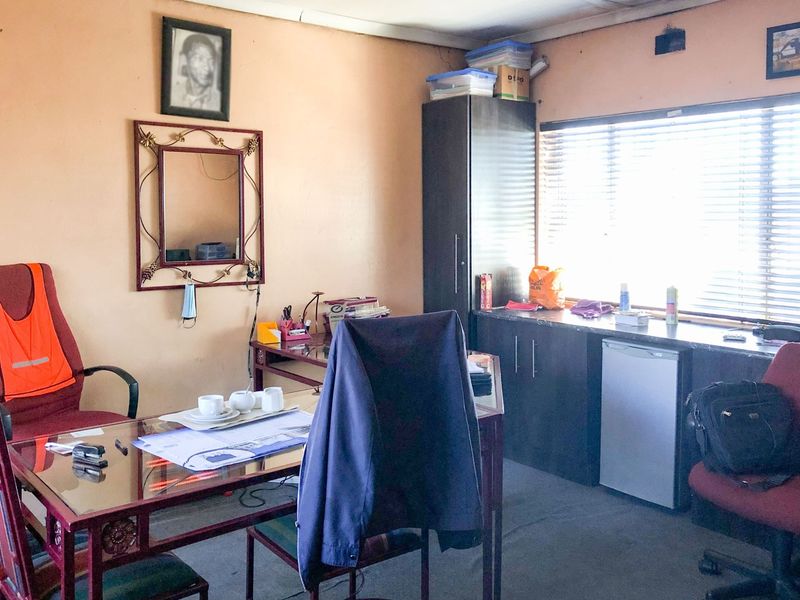 A functional office space featuring built-in cabinetry, a countertop, and venetian blinds, providing a practical workspace environment.