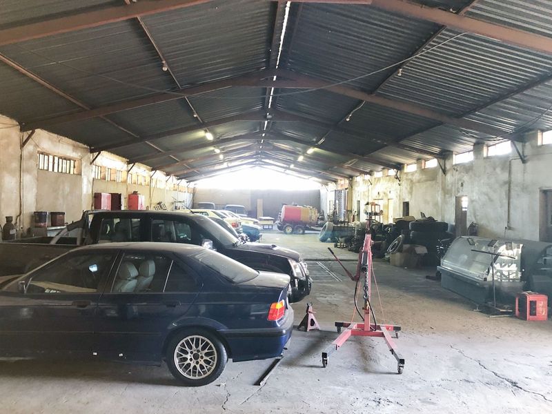 Large commercial garage or workshop space featuring high ceilings with exposed steel trusses, concrete flooring, and ample open floor area for industrial use.