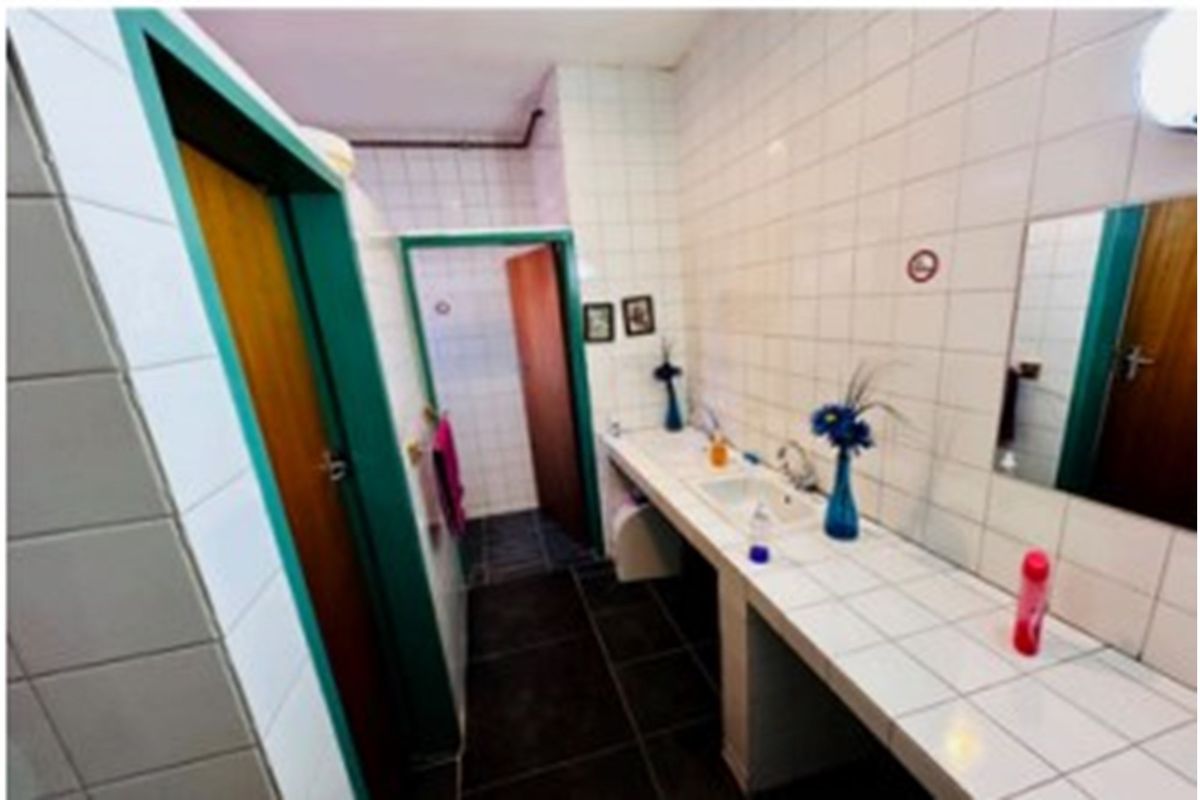 A functional bathroom area featuring a tiled vanity counter, wall-mounted mirror, and multiple doorways leading to adjacent spaces.